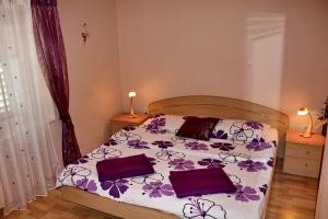 a bedroom with a bed with purple flowers on it at Apartments by the sea Brodarica, Sibenik - 20762 in Šibenik