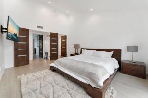 a bedroom with a large bed with white sheets and a rug at Staycation in West Los Angeles in Los Angeles