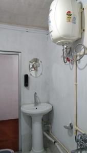 a bathroom with a white sink and a light at Damfu Basera Homestay in Kurseong