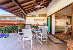 a dining room with a table and chairs on a patio at Casa em Carneiros - 4 suítes com piscina in Tamandaré