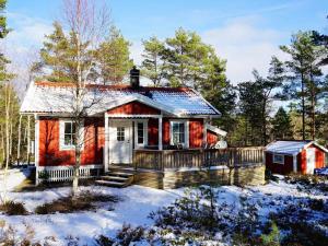 una pequeña casa roja con terraza en la nieve en Holiday home Grebbestad X en Grebbestad