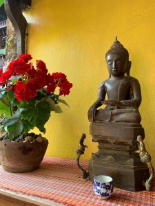 uma estátua de um Buda sobre uma mesa com flores em Hongkhao Village em Chiang Mai