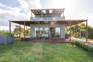 a house with a large deck with a patio at Million Dollar Views in Mangawhai