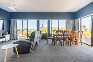 a living room with a table and chairs and a dining room at Million Dollar Views in Mangawhai