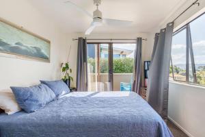 a bedroom with a blue bed and a window at Million Dollar Views in Mangawhai