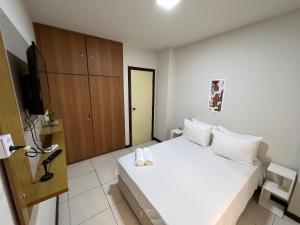 1 dormitorio con 1 cama blanca y armario en Flat Píer Sul Ondina, en Salvador