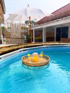 einen Pool mit einem Tisch, einem Getränk und einem Sonnenschirm in der Unterkunft กาลเวลา เกาะสีชัง in Ban Tha Thewawong