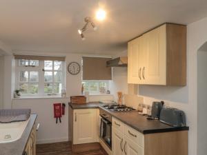 a kitchen with white cabinets and a clock on the wall at Chestnut Cottage in Scarborough