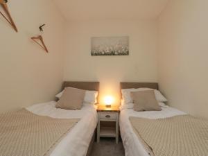 - 2 lits dans une chambre avec une lampe sur une table de nuit dans l'établissement Chestnut Cottage, à Scarborough