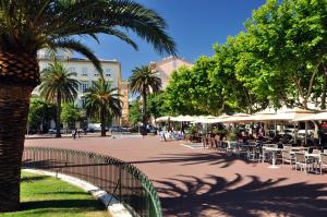 a street with tables and chairs and palm trees at Hotel Riviera in Bastia