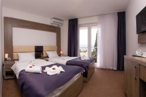 a hotel room with two beds with towels on them at Guest House Aria in Herceg-Novi