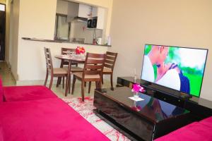 a living room with a tv and a table with chairs at RedFin Vacation Home in Vipingo