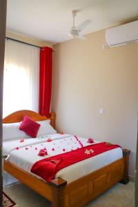 a bedroom with a bed with red sheets and a window at RedFin Vacation Home in Vipingo