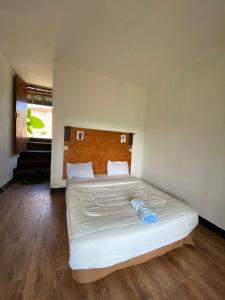 a bedroom with a white bed with a wooden headboard at Dragonfly Senaru Lodge in Senaru