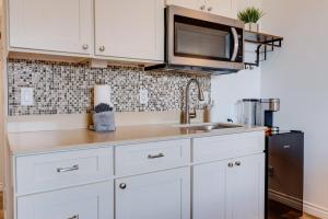 a kitchen with white cabinets and a sink and a microwave at Unit 6 Maui Ohana Modern Studio in Wailuku