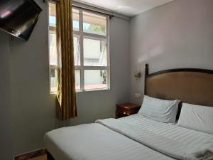 a bedroom with two beds and a window at HOTEL RK CAHAYA in Labuan