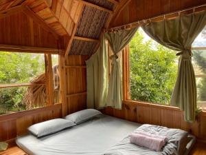 大叻的住宿－Đà Lạt Củi Homestay，一张位于带大窗户的房间内的床铺