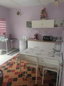 una cocina con mesa blanca y sillas sobre una alfombra en Haji Homestay - A tiny house with 2 bedrooms en Bentong