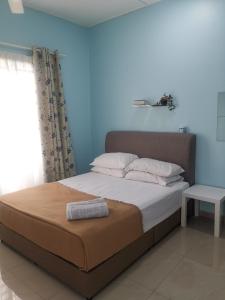 1 cama en un dormitorio con una pared azul en Haji Homestay - A tiny house with 2 bedrooms en Bentong