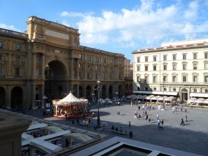 Un groupe de personnes marchant autour d'une place avec un carrousel dans l'établissement B&B Repubblica, à Florence