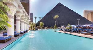 a swimming pool with chairs and a pyramid in the background at Strip Las Vegas Unit by Luxor and T Mobile arena area in Las Vegas