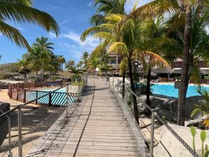 a wooden walkway leading to a beach with palm trees at Studio 4 places chez Loïc in Saint-François