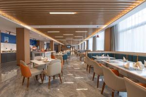 a dining room with tables and chairs and windows at Holiday Inn Express Zhengzhou Guancheng by IHG in Zhengzhou