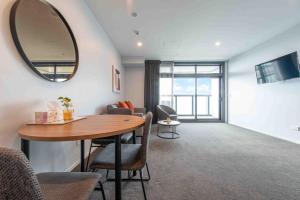 a living room with a table and a mirror at Deluxe One Bedroom Apartment in Newmarket Auckland in Auckland