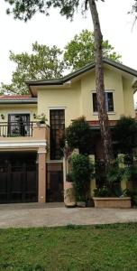 een geel huis met een boom ervoor bij Charming Getaway @ The City of Pines in Baguio