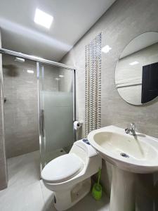y baño con aseo, lavabo y espejo. en Hotel Monaco, en Santo Domingo de los Colorados