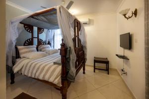 1 dormitorio con cama con dosel y TV en Nyali Villa, en Mombasa