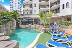una piscina con sillas azules y un edificio en 2 Bedroom Central Mooloolaba Resort with Pool, Spa, Mini Golf en Mooloolaba