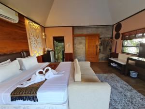 a bedroom with a large bed with white shoes on it at Naga Tara Boutique Resort in Phayao