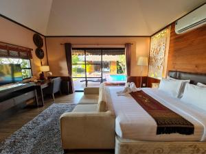 a bedroom with a large bed with a couch and a desk at Naga Tara Boutique Resort in Phayao