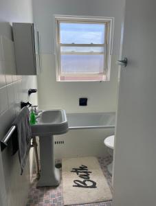 a bathroom with a sink and a toilet and a window at Eloura Gardens 100m to Beach in Cronulla
