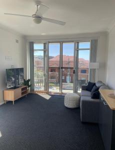 a living room with a couch and a large window at Eloura Gardens 100m to Beach in Cronulla