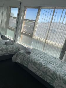 a bedroom with two beds and a large window at Eloura Gardens 100m to Beach in Cronulla