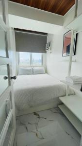 a white bedroom with a bed and a window at San Lorenzo Place in Manila