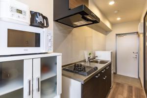a small kitchen with a microwave and a sink at Yukurina Resort Okinawa in Motobu