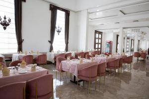 uma sala de jantar com mesas e cadeiras com toalhas de mesa cor-de-rosa em The Utopia Resort Sanchi em Sānchi