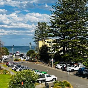 a parking lot with cars parked in front of the ocean at Eloura Gardens 100m to Beach in Cronulla