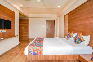 a bedroom with a large bed and a flat screen tv at FabHotel Mahadev Residency in Kolshet