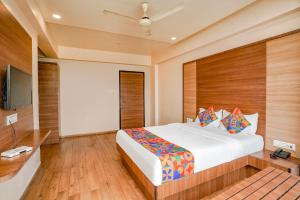 a bedroom with a large bed and a flat screen tv at FabHotel Mahadev Residency in Kolshet