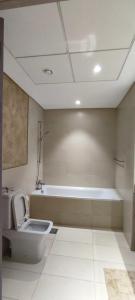 a bathroom with a toilet and a bath tub at Smart Living Apartment in Abu Dhabi