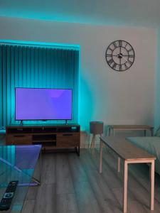 a living room with a flat screen tv and a clock at 5 Bed Town House Within City Centre and Sleeps Up To 11 with Sky and Netflix in Birmingham