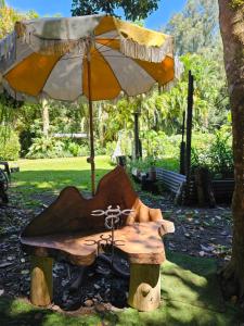 une table en bois avec un parasol sur un banc dans l'établissement Garden Studio, à Jaggan