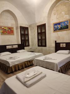 um quarto com três camas com toalhas em JOSELİN HOTEL em Şanlıurfa