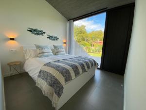 a bedroom with a bed and a large window at La Casa de Hierba - Casa de campo de diseño con jardín y wifi cerca de las playas de Llanes in Llanes