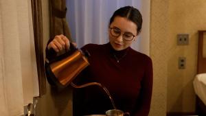 una mujer está vertiendo líquido en un recipiente de mezcla en COFFEE HOTEL Soundwave, en Fujisawa
