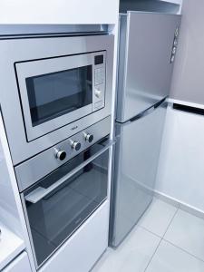 un frigorifero in acciaio inossidabile con forno a microonde in cucina di Beacon Executive Suites #Georgetown #RoofTopPool #Spacious #13a a George Town